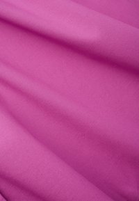 Tessuto di cotone rosa con una texture liscia, che presenta pieghe e grinze sottili, formando un lieve motivo a onda sulla superficie.