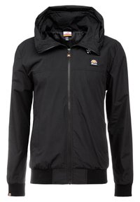 Svart lättviktsjacka med dragkedja fram, justerbar huva, ribbade mudd, och logotypdetalj på bröstet. Slät, matt tygtextur.