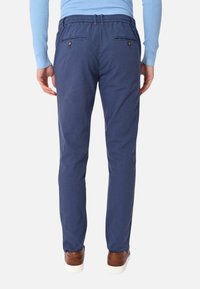 Pantaloni di cotone blu navy con una texture liscia, dotati di due tasche posteriori con chiusura a bottone e un design dalla vestibilità rilassata.