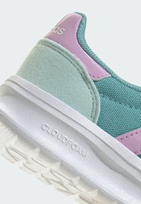 Gros plan sur un talon de sneaker teal et lavande avec une semelle blanche texturée embossée "CLOUDFOAM" et des sections supérieures en tissu et en daim.