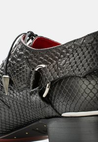 Schwarze Schlangenleder-Schuh mit strukturierter Oberfläche, ausgestattet mit rotem Innenfutter, silbernen Hardware-Akzenten und einem niedrigen Holzabsatz. Schnürsenkel inklusive.