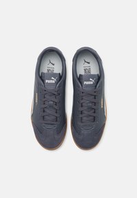 Baskets de sport bleu marine avec une tige en daim et en synthétique, fermeture à lacets, accents blancs et semelle extérieure en caoutchouc brun. Logo PUMA affiché.