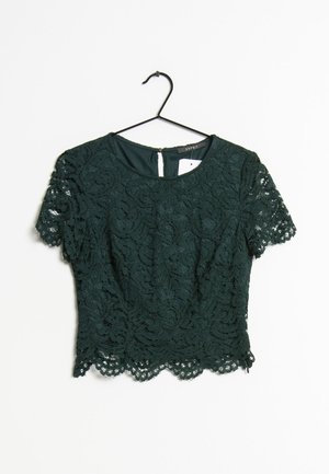 Dark green lace short-sleeve crop top with floral pattern, scalloped hem, and round neckline hanging on a black hanger.