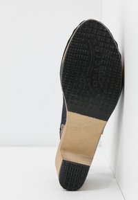 Svart gummisula med texturerat grepp, trä-mellansula och en marinblå ovansida med en kurvad design. Positionerad mot en vit bakgrund.