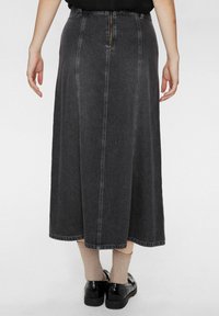 Fekete denim midi szoknya egyenes szabással, látható varrással, hátsó cipzárral és használt hatással. Ribbed zoknikkal és cipővel viselve.
