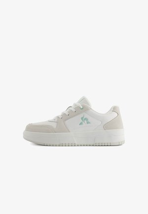 Białe sneakersy z jasnoszarymi zamszowymi akcentami, z zaokrąglonym czubkiem, sznurowanym wzorem i logo z boku. Teksturowana gumowa podeszwa.