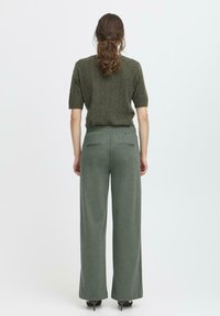 Top scurt cu mânecă, texturat, de culoare verde, asortat cu pantaloni largi, de un verde deschis, care au două buzunare la spate și un elastic la talie.
