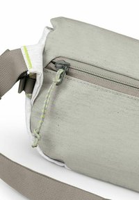 Borsa in tela grigia con finitura testurizzata, dotata di una tasca con cerniera, bordi bianchi a contrasto e una tracolla beige regolabile.