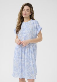 Jasnoniebieska sukienka z białym wzorem paisley, krótki rękaw, okr�ągły kołnierzyk, zapięcie na guziki z przodu i marszczona talia, wykonana z lekkiego materiału.