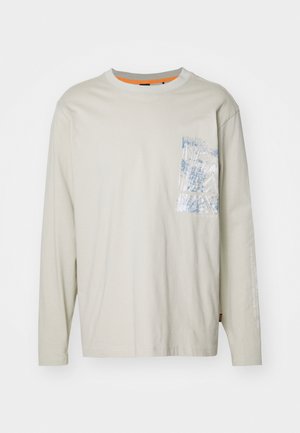 Long-sleeve light beige t-shirt made of cotton. Features a blue patterned chest pocket and orange detailing on the collar.