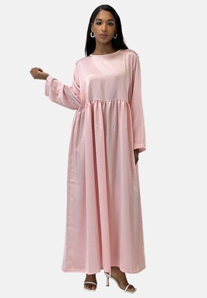 Roze satijnen lange jurk met lange mouwen, ronde halslijn, geraffineerde taille en vloeiende zoom. Draag met open teenschoenen en decoratieve oorbellen.