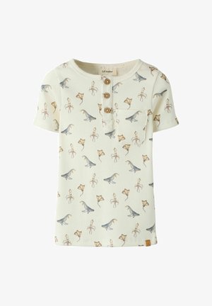 Camiseta infantil corta de manga corta en color crema, con textura acanalada, botones de madera, pequeño bolsillo en el pecho y estampado de dinosaurios y mantarrayas.