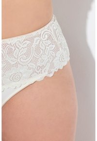 Witte onderkleding met kantdetails, voorzien van een brede, geschulpte tailleband en een glad, naadloos lichaam, waarin bloemmotieven in het kant zijn verwerkt.
