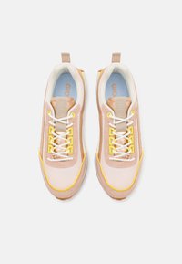 Light pink sneakers with mesh and suede materials. Features yellow accents, white laces, and a blue insole. Rounded toe and padded collar.