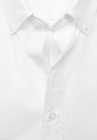 Weißes Baumwollhemd mit Kragen, das ein Button-Down-Design und eine Schlitzöffnung am Ausschnitt aufweist. Weicher Stoff, klare Linien.