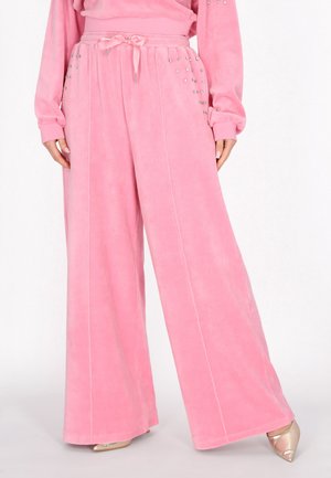 Weit geschnittene, weich rosa Hose mit Kordelzug in der Taille und kleinen silbernen Nieten an den Taschen, getragen mit passendem Oberteil und beigen spitzen Schuhen.