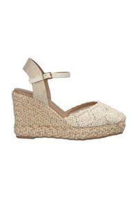 Wedge sandaal in beige en room, met een bovenwerk van textuurstof met een gebloemd haakpatroon en een gevlochten jute zool. Verstelbare enkelband.