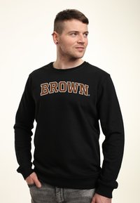 Zwarte sweatshirt van een katoenmix met een grote "BROWN" in bruin gedrukt op de borst. Aansluitende boorden en een ronde hals.