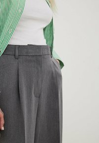 Gray pleated trousers with a tailored fit, featuring belt loops and side pockets, paired with a green and white striped shirt.