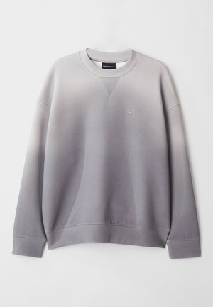 Szürke pulóver, amely fokozatos színátmenettel, bordás mandzsettákkal és szegéllyel, valamint egy kis logóval rendelkezik a bal mellen. Puha pamutkeverékből készült.