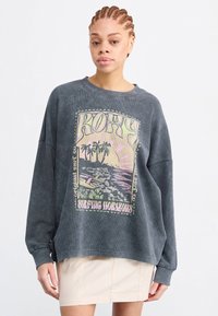 Overmaat grijze sweatshirt met een kleurrijke surfthema-afbeelding, featuring palmbomen en golven, geribbelde textuur en brede mouwen.