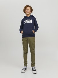 Felpa navy con logo bianco "JACK & JONES", tasca a marsupio. Pantaloni cargo oliva con tasche laterali. Sneakers nere e bianche con lacci.