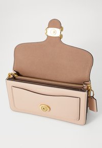 Leather handbag in pale pink with a smooth texture, gold hardware, front pocket, and a zippered interior compartment.