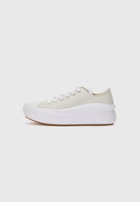 Kremfargede kanvas-sneakers med hvite snørebånd, hevet hvit gummisåle og gummisåle. Rund tå og minimale design detaljer.