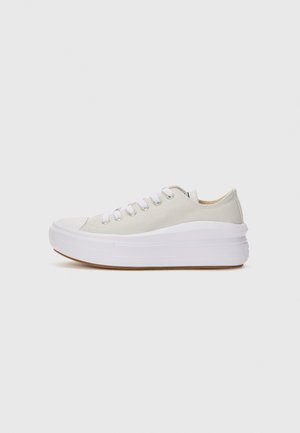Cream canvas sneakers with white laces, raised white rubber sole, and a gum outsole. Rounded toe and minimal design details.