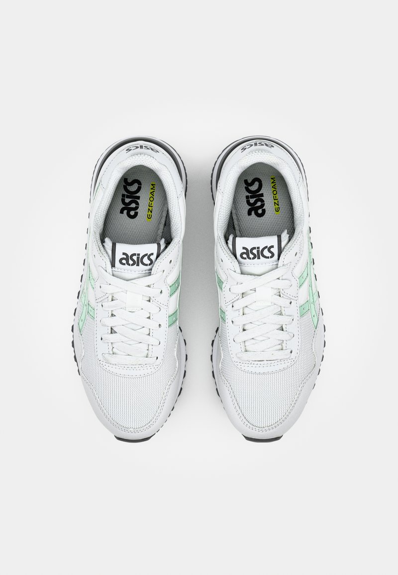Sneaker bianche in rete con dettagli verdi, punta rotonda, design con lacci e suola in gomma nera. Logo visibile sulla linguetta e sui lati.