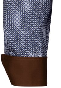 Camicia a maniche lunghe con un motivo geometrico blu su sfondo bianco, con polsini solidi marroni. Tessuto in cotone, con una texture liscia.