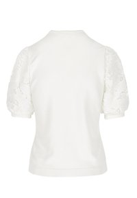 Top bianco a maniche corte con corpo in tessuto solido e maniche a sbuffo in pizzo floreale trasparente, polsini e orlo a coste su uno sfondo semplice.