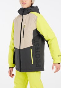 Skijack met een kleurblokontwerp in zwart, beige en felgeel, voorzien van ritsen en een capuchon. Merken zichtbaar op de onderzijde van de voorkant.