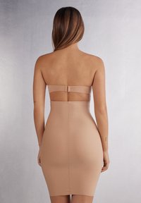 Béžové bezramínkové pouzdrové šaty s elegantním designem, hladkou texturou a přiléhavým střihem se zapínáním na zádech.