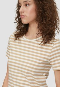 Röstribade T-särk beeži ja valge värviga, valmistatud pehmest puuvillast. Ümmargune kaelus, lühikesed varrukad ja sobiv disain. Peene tekstuur ja ühtlane muster.