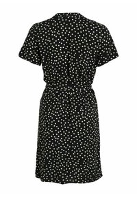 Robe noire à manches courtes avec motif à pois carrés blancs, taille cintrée et ourlet au genou, vue de dos.