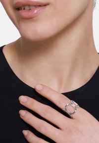 Das Set aus silbernem Metallringen verfügt über einen abgerundeten Band mit zwei miteinander verbundenen geometrischen Formen. Glatte Textur, minimalistisches Design, am Finger getragen.