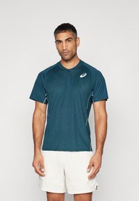 Korte mouwen teal sportpoloshirt met een gestructureerd patroon, drieknops sluiting en reflecterende accenten. Witte logo op de borst.