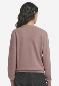 Jasnoróżowy sweter z okrągłym dekoltem, długimi rękawami oraz prążkowanymi mankietami i dolnym wykończeniem. Miękka faktura, dopasowany krój i minimalne detal.