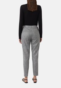 Grijze geruite broek met een tapered fit, voorzien van een klassieke tailleband en twee achterzakken, gecombineerd met een zwart long-sleeve top.