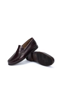 Mocasines de cuero marrón oscuro con un diseño cosido, estilo sin cierre y suela de goma texturizada. Presentan un acento de silla en la parte delantera.