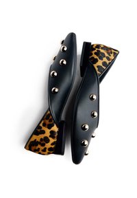 Ballerines en cuir noir ornées de clous dorés sur le dessus. Le talon présente un motif léopard, associant textures et couleurs contrastées.