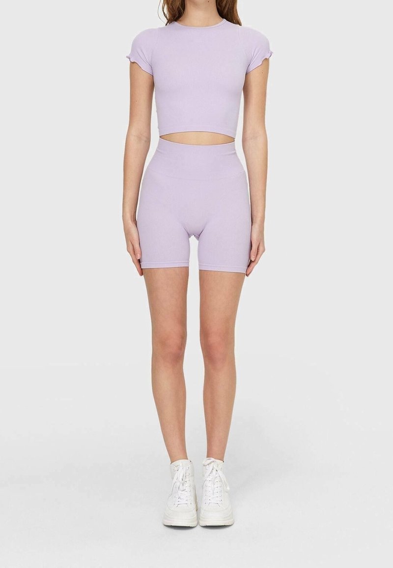 Conjunto de dos piezas en púrpura claro que incluye un top corto con mangas cortas y pantalones cortos de cintura alta, fabricado con una tela suave y elástica.