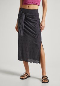 Falda midi gris oscuro con recortes florales y un lazo anudado en la cintura. Presenta un dobladillo con puntilla y una abertura lateral, hecha de tejido ligero.