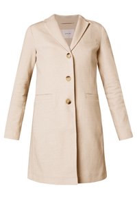 Cappotto beige su misura con rever a lancia, tre bottoni, due tasche frontali e maniche lunghe realizzato in un tessuto morbido.