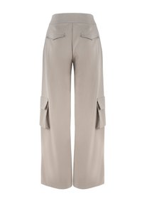 Beige wijde broek met een zachte textuur, voorzien van twee cargopockets aan de zijkanten en een hoge tailleband. Achterzakken zijn ook zichtbaar.