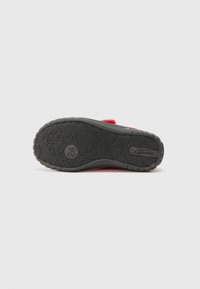 Sandale rouge à glissière avec une semelle en caoutchouc texturée, présentant un profil bas et un motif hexagonal. Le lit de pied est rembourré pour plus de confort.