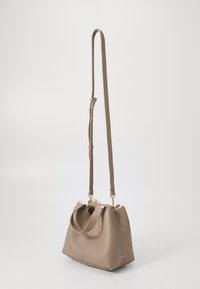 Brown textured leather bag with a rounded shape, dual short handles, and a long adjustable strap. Features gold hardware accents.