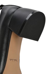 Zapato de tacón alto negro con un tacón rectangular curvado y brillante, parte superior de cuero texturizado y una plantilla beige con un logo escrito a mano.