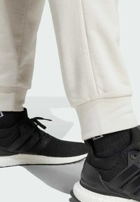 Svarta sportskor med en texturerad ovandel, vit mellansula och snören, ihopparade med ljusbeige joggers med ribbade muddars.